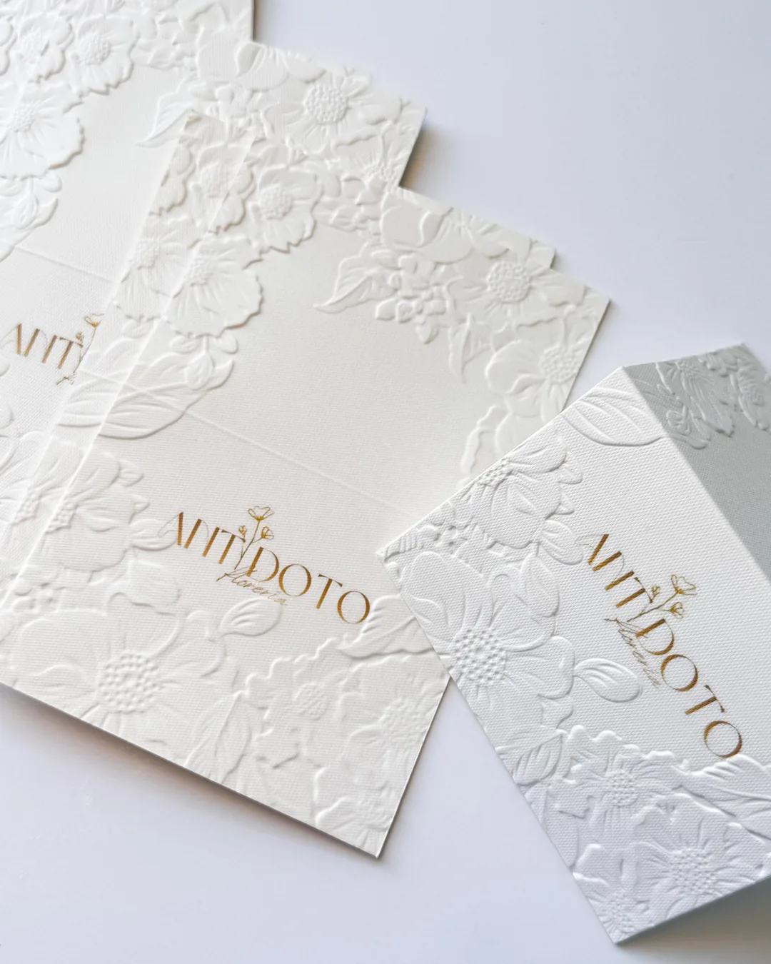 Carpetas blancas con flores en relieve y logotipo dorado