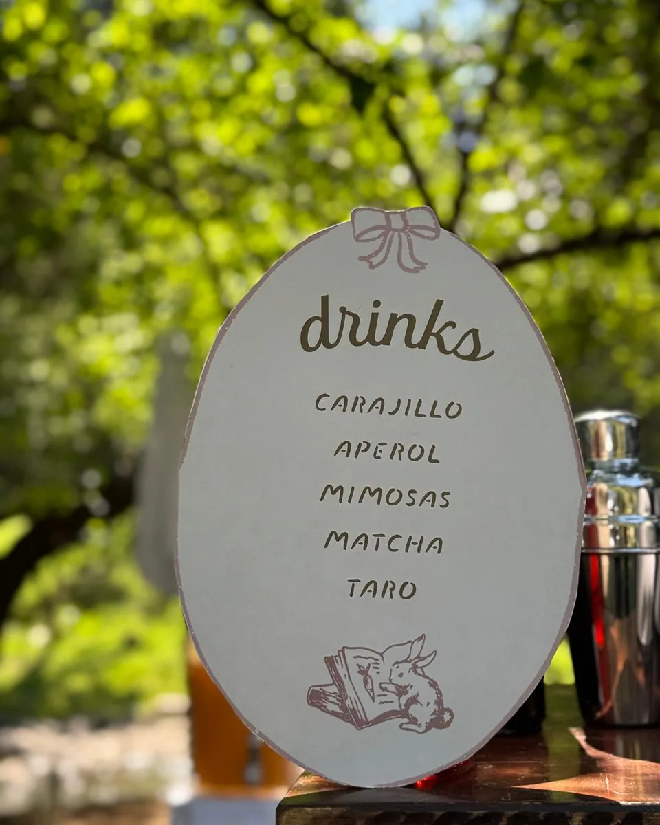 Letrero ovalado con el menú de bebidas, en un jardín