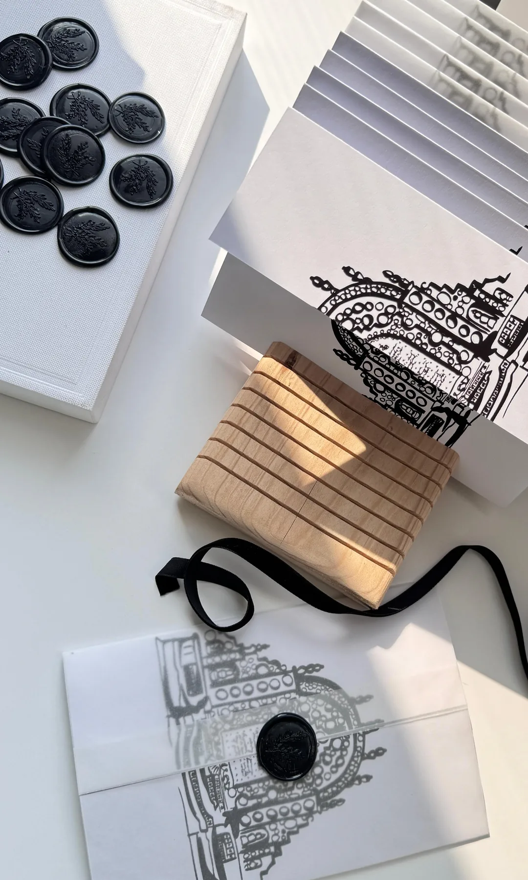 Invitaciones con la ilustración de una catedral en tinta negra, sellos de lacre negros, un sobre translúcido y listón de terciopelo